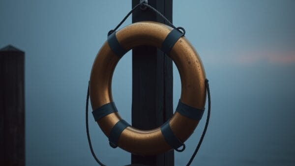 Bouee de sauvetage en laiton accrochee a un poteau de quai avec brume et lueur ambre