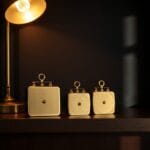 Trois poids anciens en laiton alignés sur une étagère en bois sombre sous lampe chaude