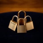 Trois cadenas en laiton de differentes formes imbriques en triangle sur velours sombre