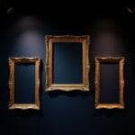 Trois cadres en laiton ornés de styles différents accrochés vides dans une galerie