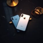 Deux smartphones face visible sur granite sombre separes par un diviseur en laiton