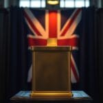 Urne en laiton avec fente pour pieces sur un podium avec drapeau britannique