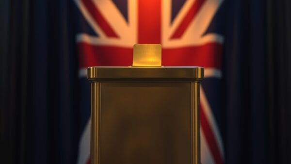 Urne en laiton avec fente pour pieces sur un podium avec drapeau britannique