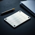 Plaque métallique de sauvegarde posée sur une surface en ardoise avec un stylo