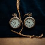 Deux montres a gousset vintage cote a cote sur du velours sombre avec une chaine en or