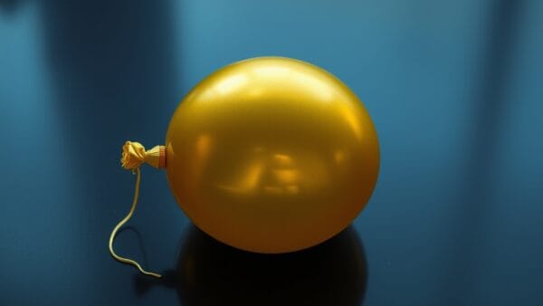 Ballon dore degonfle pose sur un sol sombre poli avec ficelle trainant dans l ombre