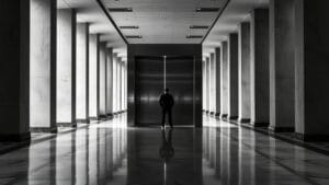 Ethereum Institutional : comprendre l'organisation pro-institutions 10 Lourde porte d'acier entrouverte dans un couloir institutionnel désert, silhouette de dos au loin.