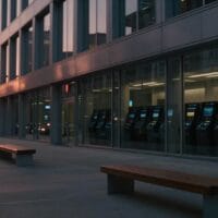 Façade vitrée d'un immeuble financier au crépuscule, plaza en béton et silhouette lointaine de dos