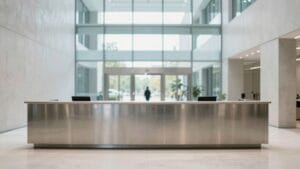 Hall d'un immeuble financier moderne, béton clair et verre, silhouette lointaine de dos