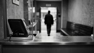Guichet de transfert d'argent en noir et blanc, comptoir métallique, silhouette de dos au loin